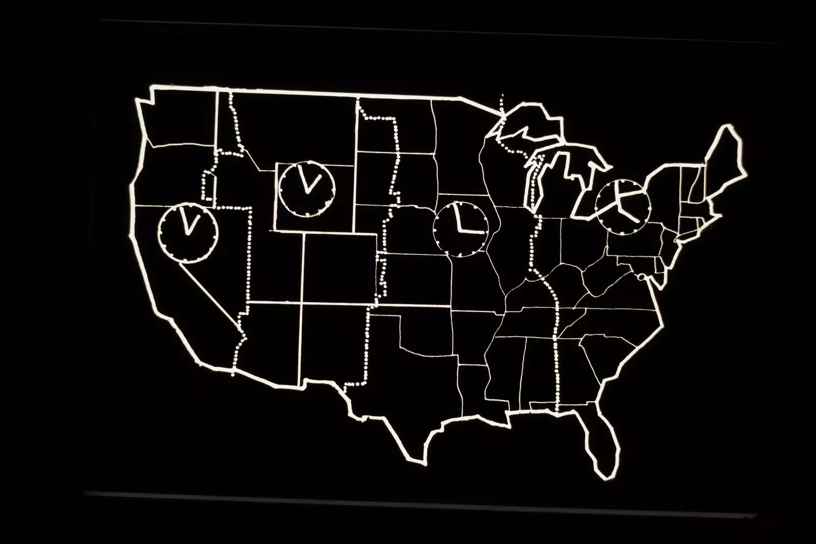 Black and white still from Laurie Anderson's United States Parts 1–4, showing the outline of the USA with four clocks inside
