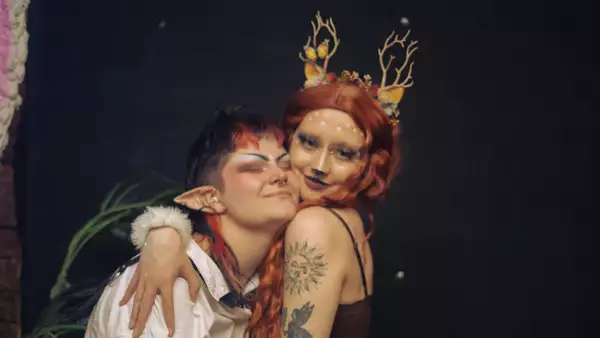Char and Mars dressed in a headdress and elf ears, smiling and hugging each other
