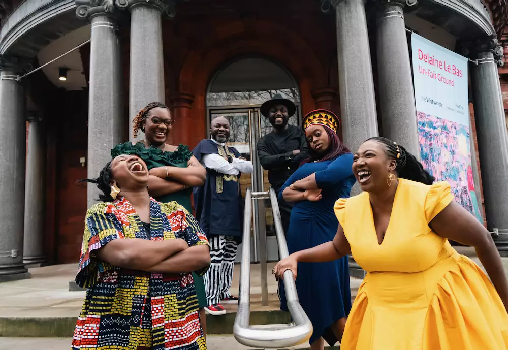 A group of people including Adeola and Ronke Jane Adelakun smiling and laughing on the steps of the Whitworth art gallery