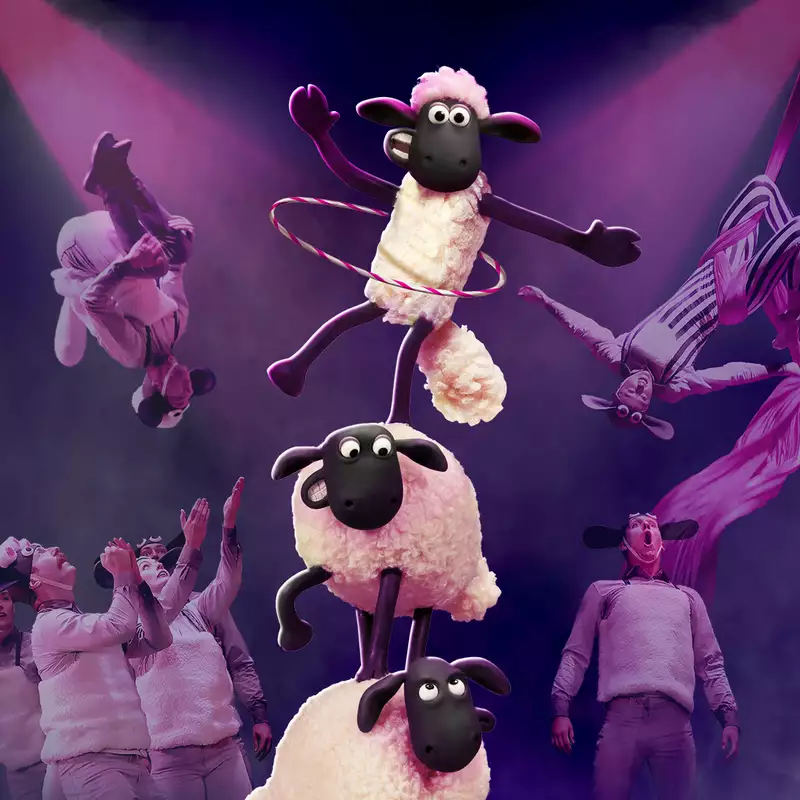 Performers in sheep costumes execute acrobatic stunts and aerial silk acts under dramatic pink lighting. In the center, three animated sheep from "Shaun the Sheep" balance in a tower, with the top one hula-hooping.