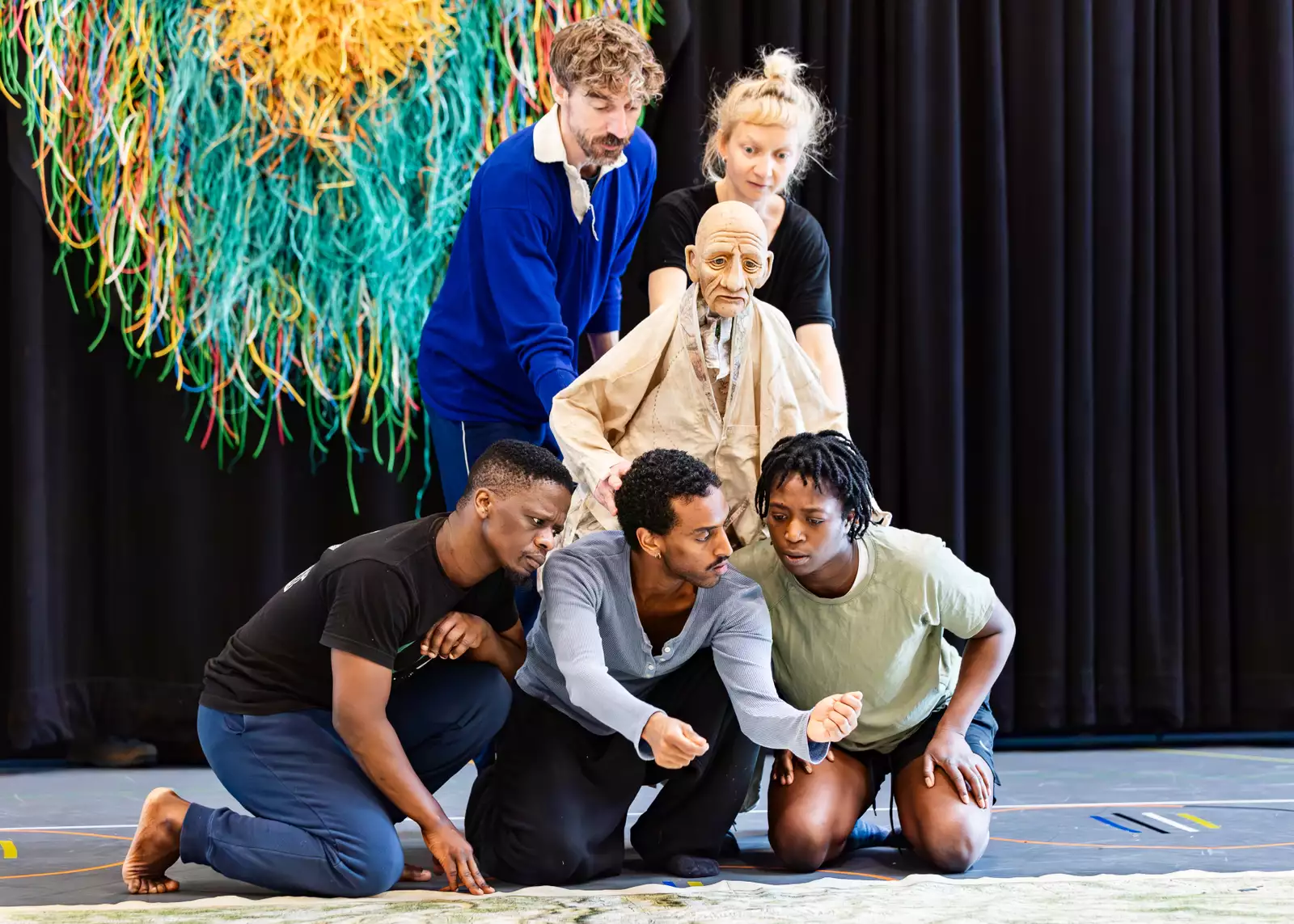 Five people pose with a map puppet in a rehearsal room