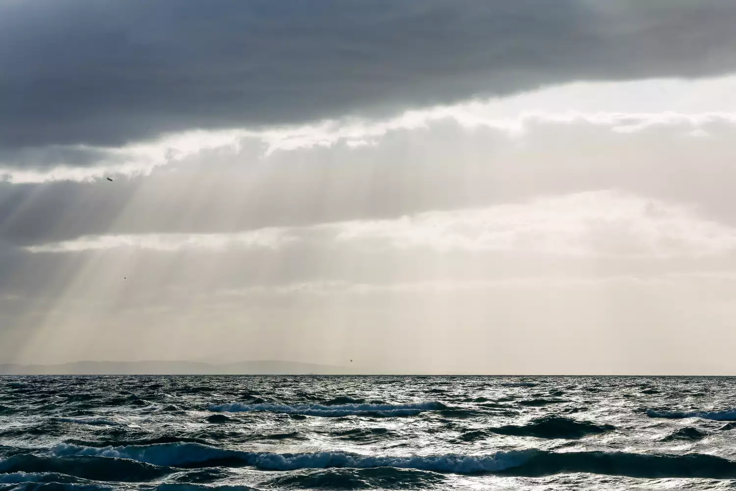 The sea with the sun peering through the clouds above