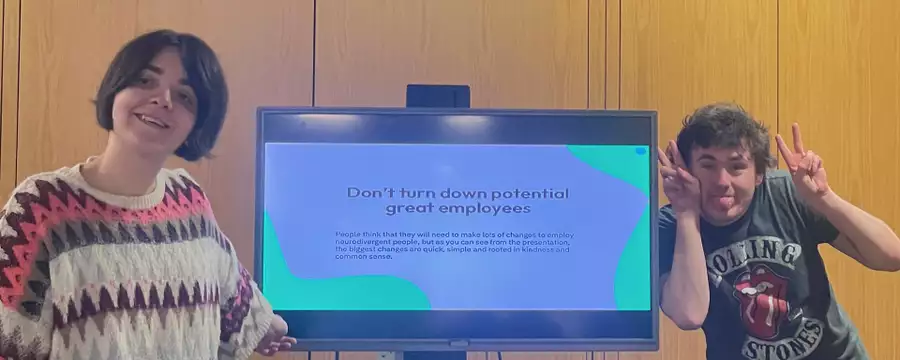 Two people stood in front of a screen which says 'Don't turn down potential great employees'