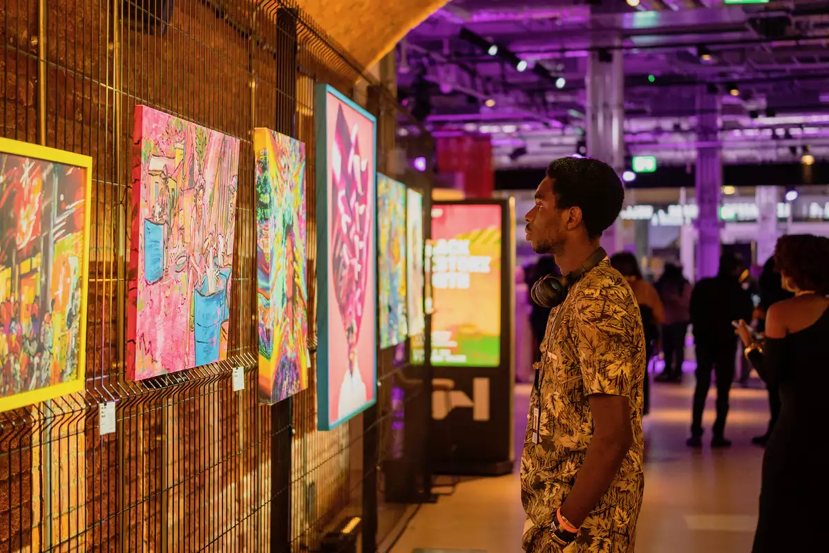 A person looking at a series of paintings on the wall of the SIM Tunnel in the Social