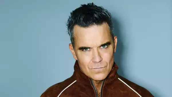 Robbie Williams on a light blue background