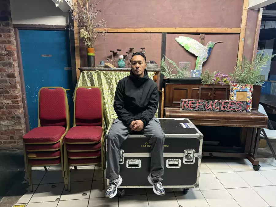 Anton Phung backstage surrounded by stacked chairs, a piano and kit boxes