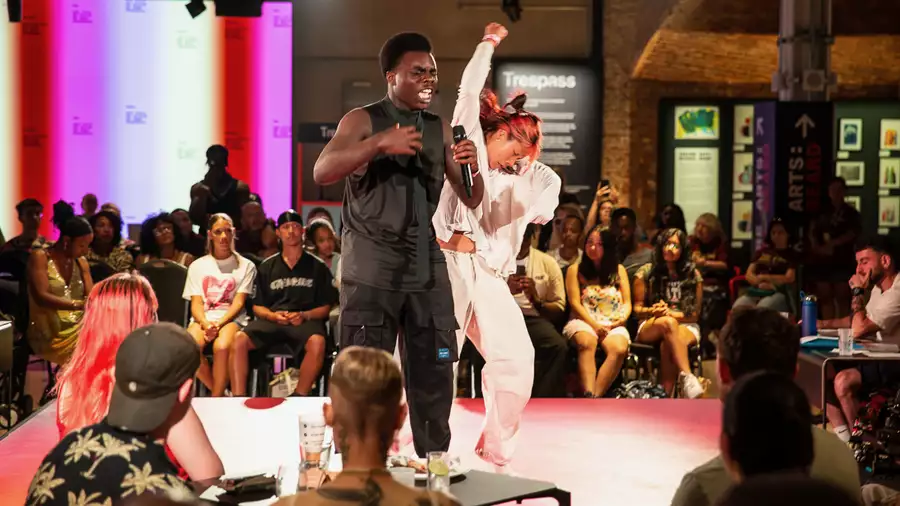 A crowd of people in the Social watching a dancer and poet perform on a stage in the centre