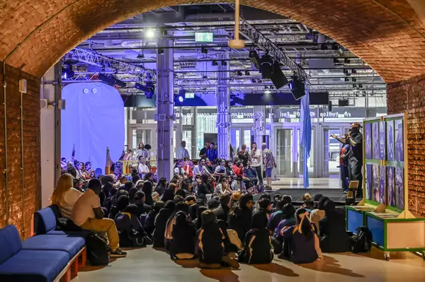 A large group of children sat on the floor of the Social, watching a performance on the stage