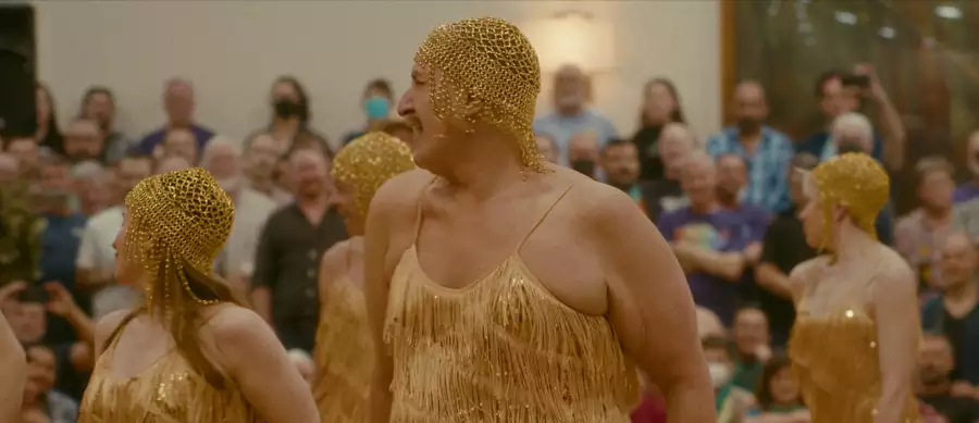 Four dancers in gold costumes dancing in front of a crowd