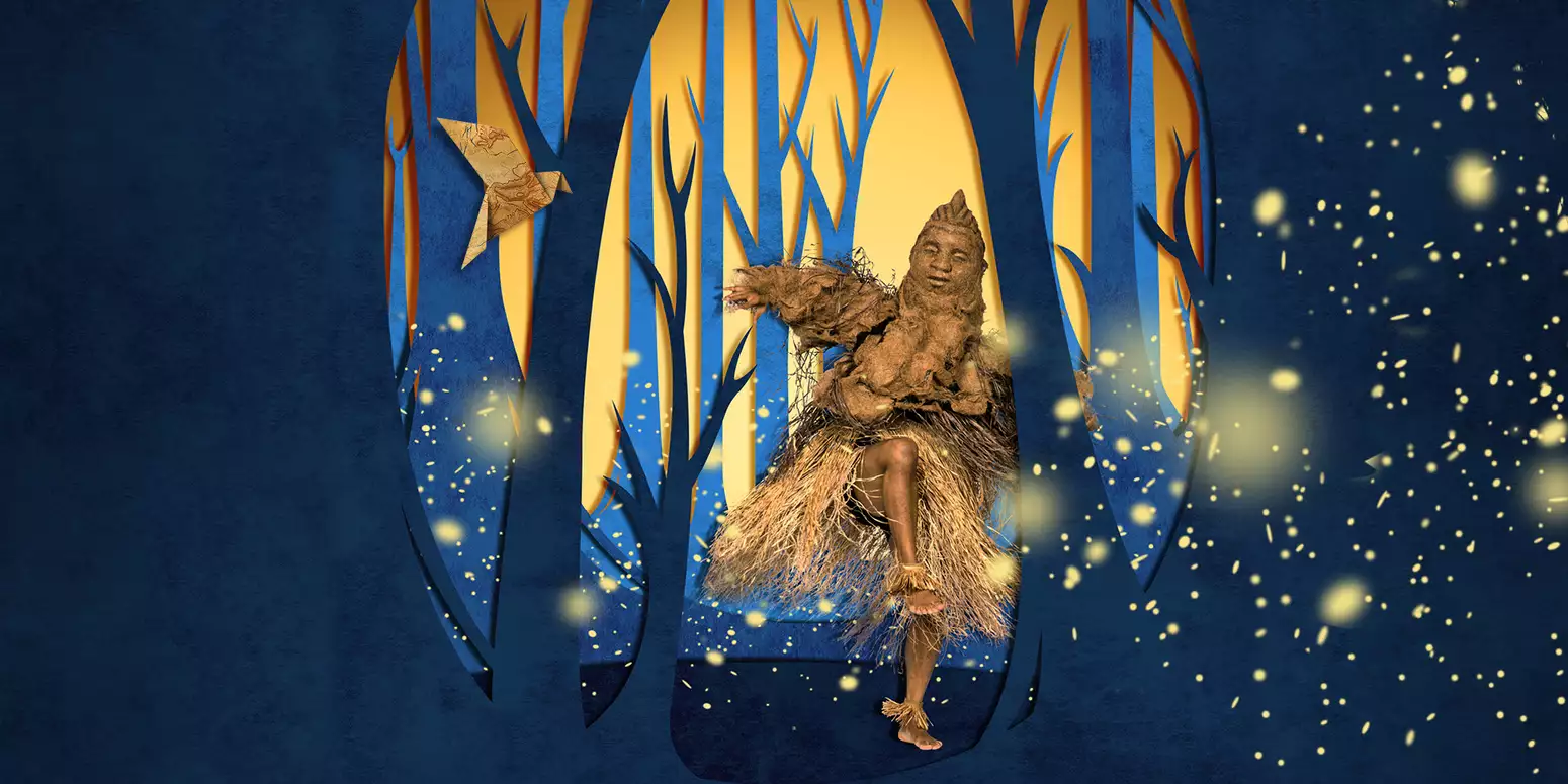 A dancer wearing a light brown costume and puppet mask, moves in a glowing forest of tall blue and golden trees, surrounded by floating firefly-like lights.