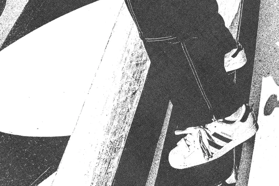 Black and white image of someone skateboarding on an Adidas skate ramp wearing Adidas trainers