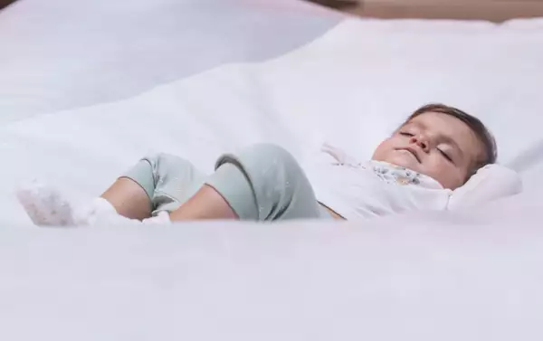 A baby sleeping on white bedding