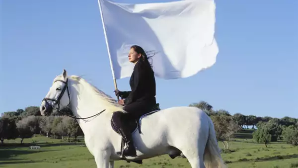 Marina Abramović on a white horse holding a white flag