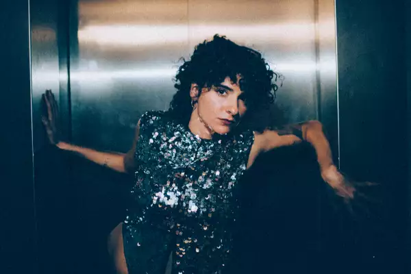 Rasha Nahas stood in a lift wearing a silver glittery dress