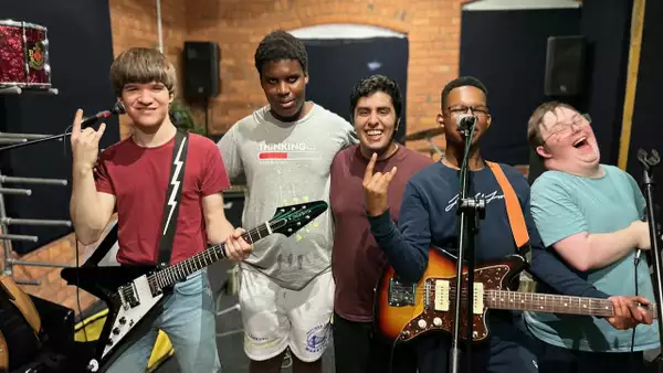 Five members of Lightening power smiling and laughing with their guitars