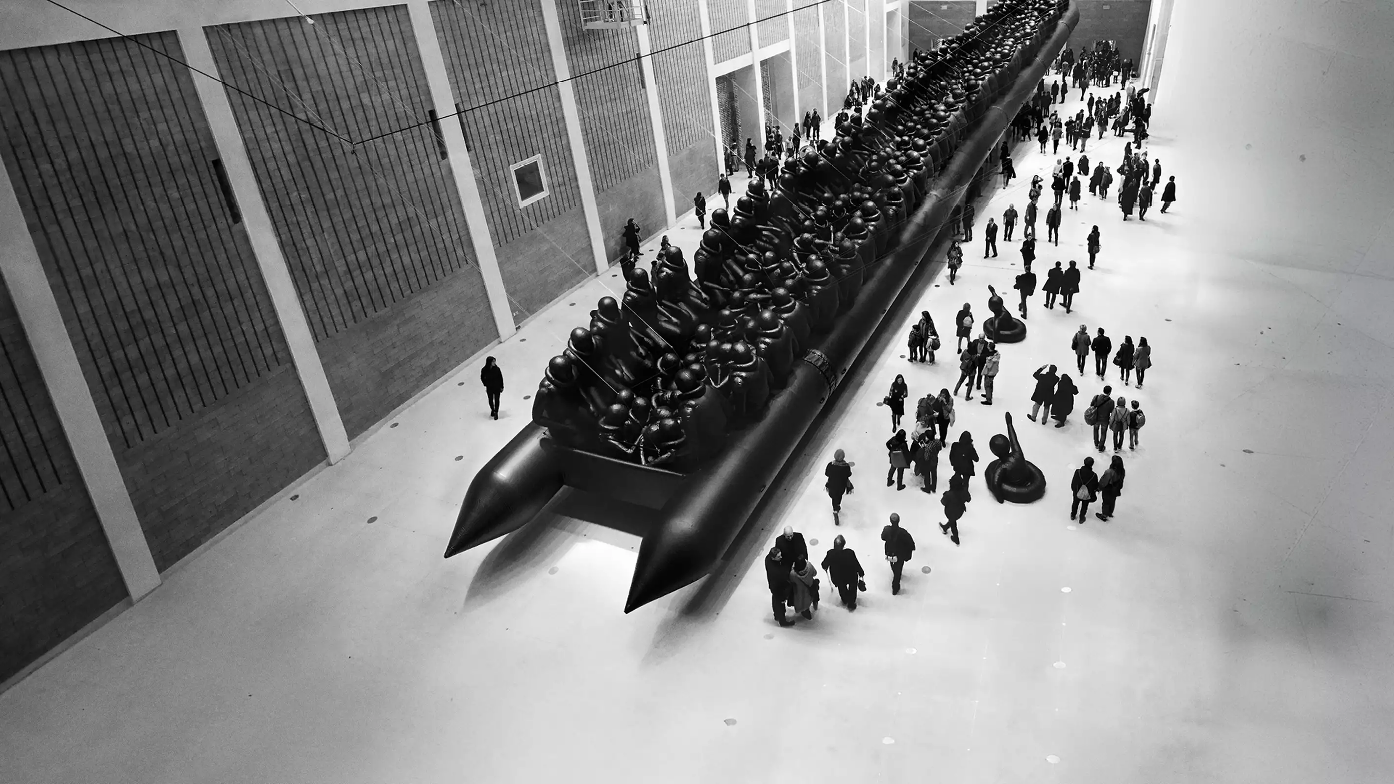 Ai Weiwei's Law of the Journey artwork, showing a crowd of people surrounding a huge, inflatable migrant boat in a big warehouse