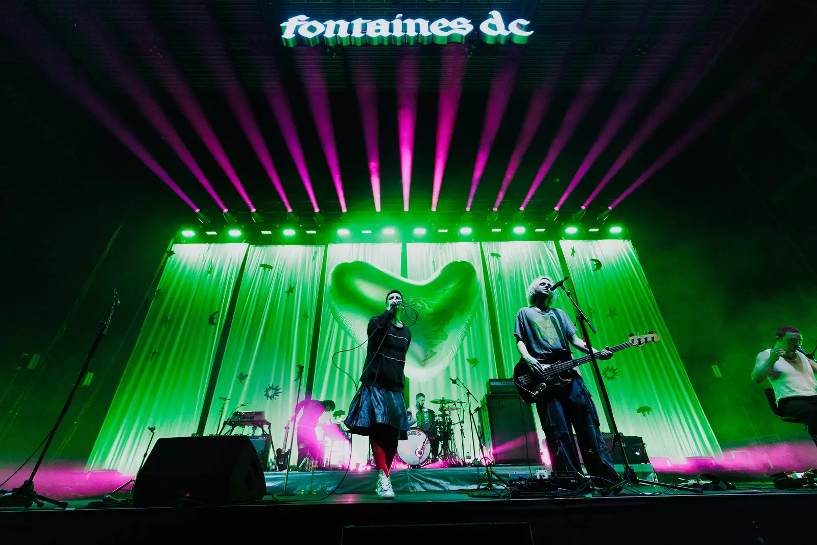 Fontaines D.C. stood on stage with a green lit background