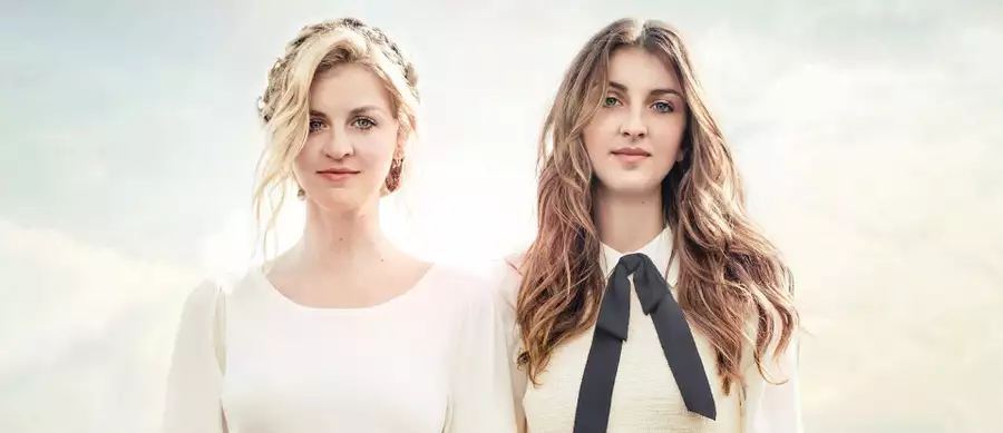 Two members of Ward Thomas stood against a pale sky background smiling