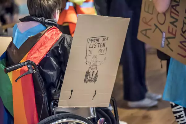 A cardboard sign which reads 'Maybe just listen to me?'