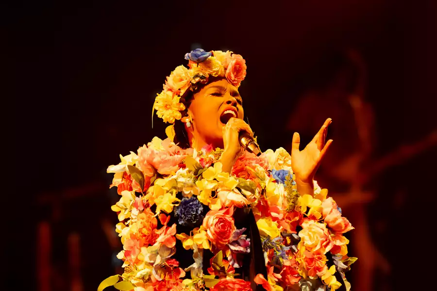 Janelle Monae sings while wearing a flower crown and flower embroidered jacket