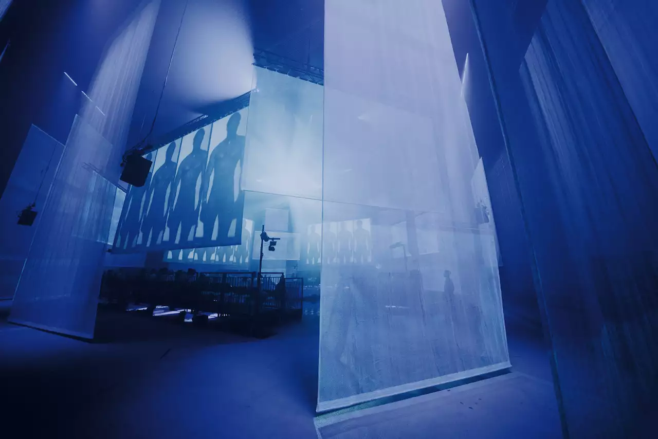 The set of A Symphony of Flesh and Bones in the Warehouse, showing projections on large screens and pieces of fabric