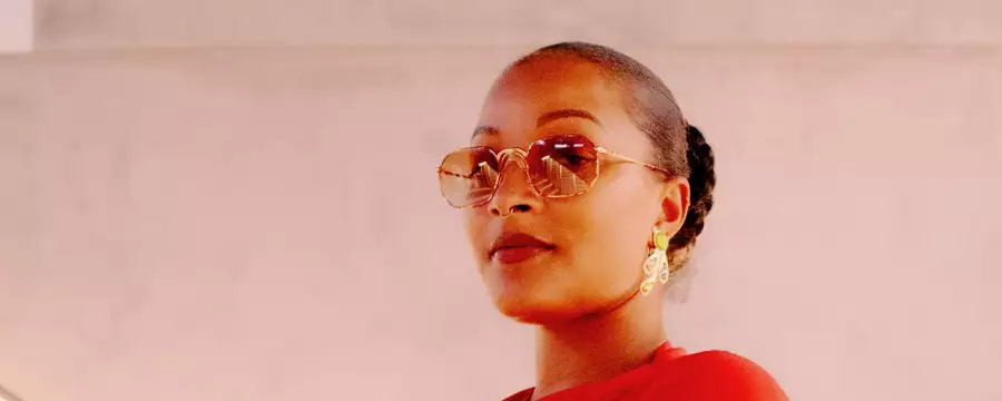 Headshot of Nubya Garcia wearing sunglasses against a pale pink-grey background