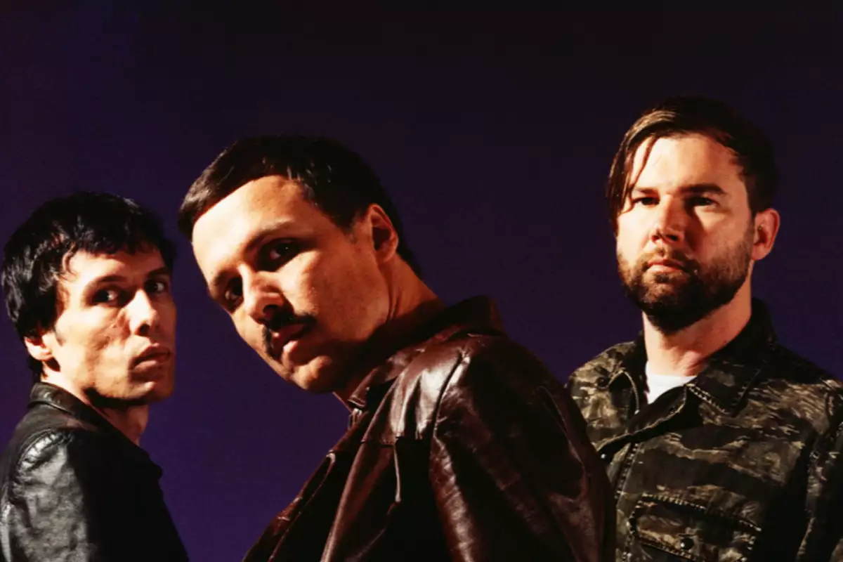 Three members of The Cribs on a dark purple background