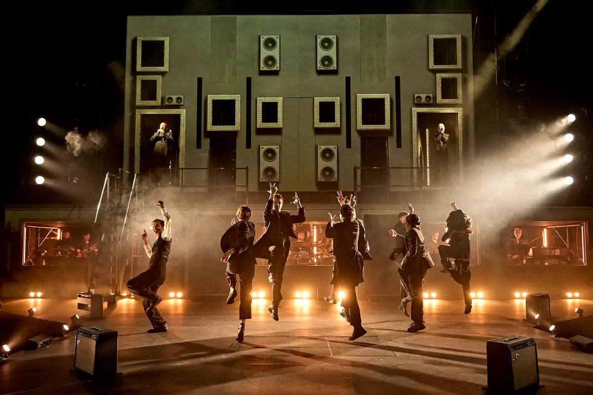 Performers jumping on stage against a castle backdrop in Hamlet Hail to the Thief