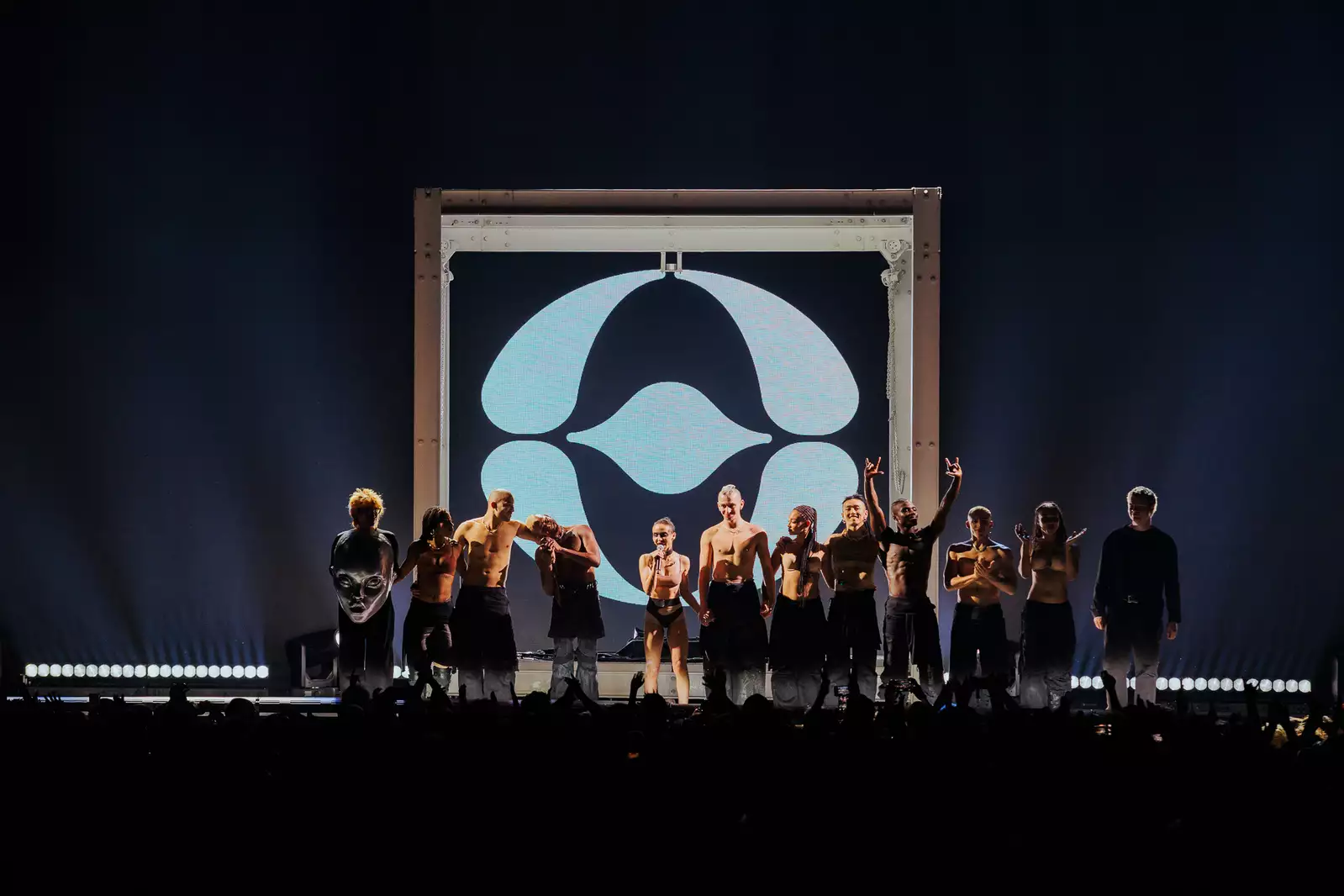 FKA Twigs on stage with her performers, stood in a line. With a large crowd watching.