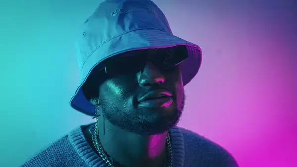 KingXton wearing a bucket hat and sunglasses on a pink and blue background