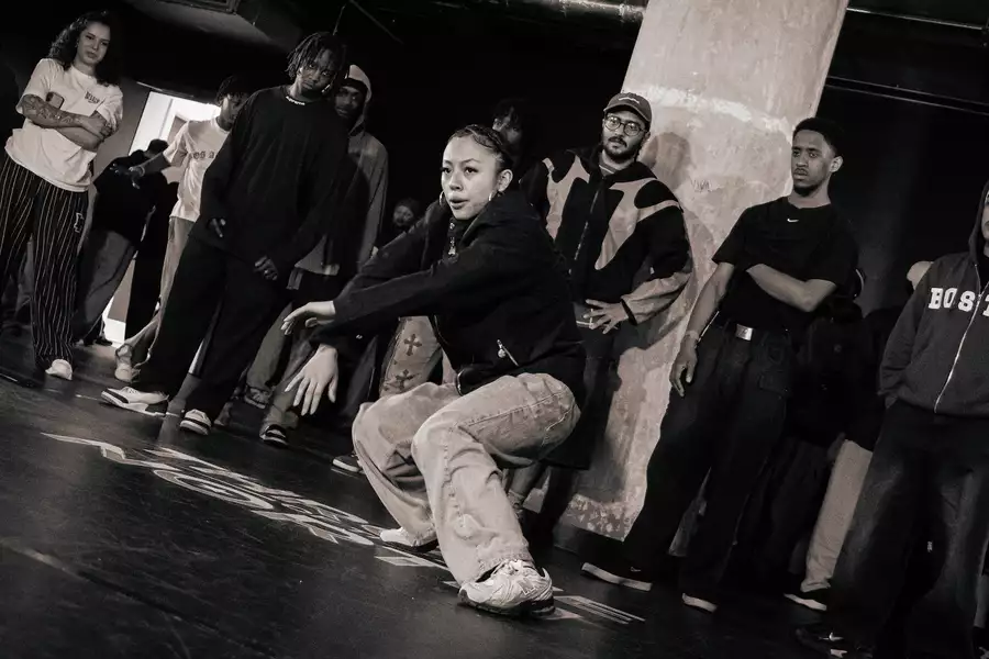 Black and white photo of a crowd of people watching a dancer in the centre