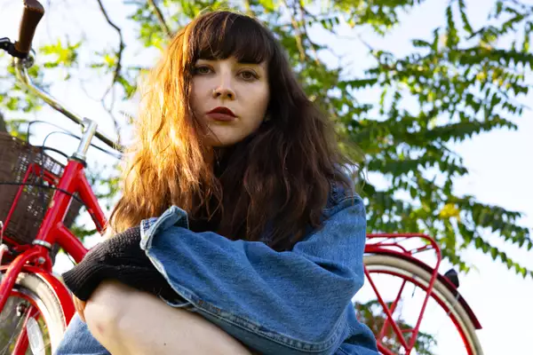 Dilettante outside, with a red bicycle behind them