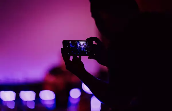 A person takes a picture on their phone at a live event.