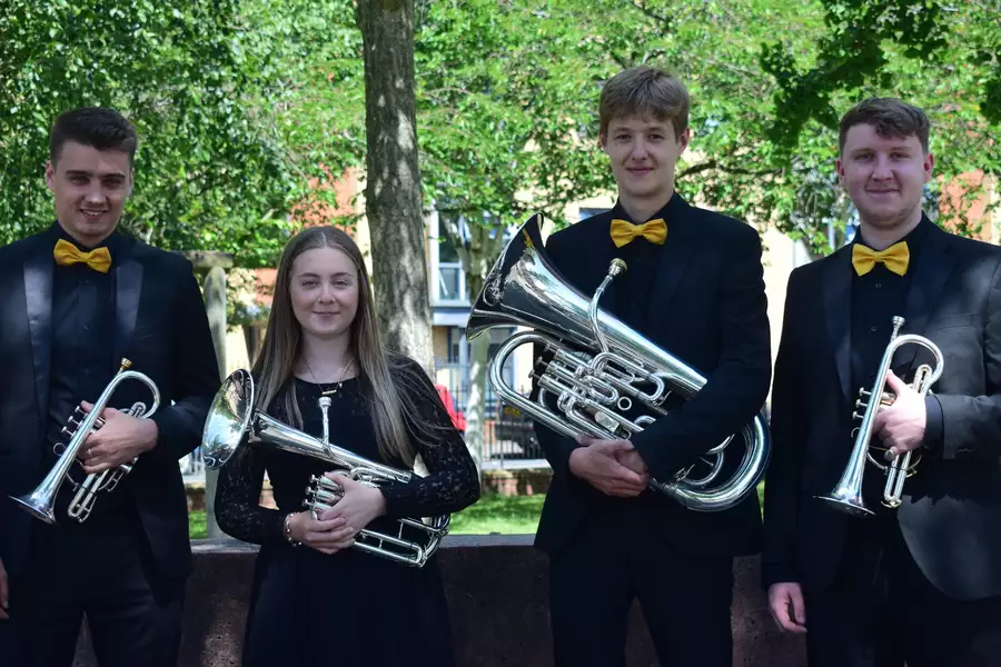 The Rosamund Brass Quarter stand in front of trees dressed in black holding their instruments