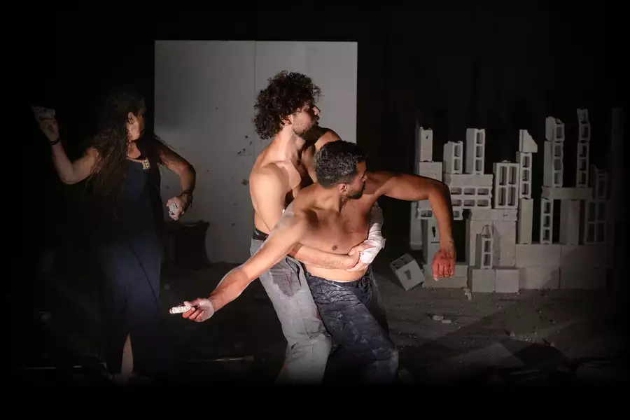 Three performers on stage during Deadlift. Two are wrestling with their arms around one another.