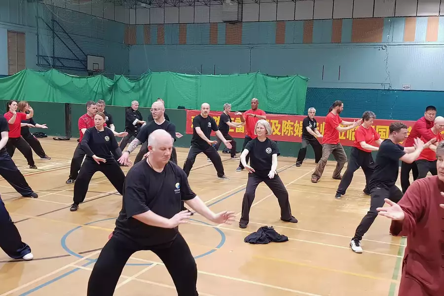 A group of people doing a qigong class in a sports hall