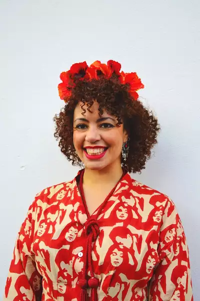 Headshot of Kinnetia Isadore wearing a bright red dress and headband