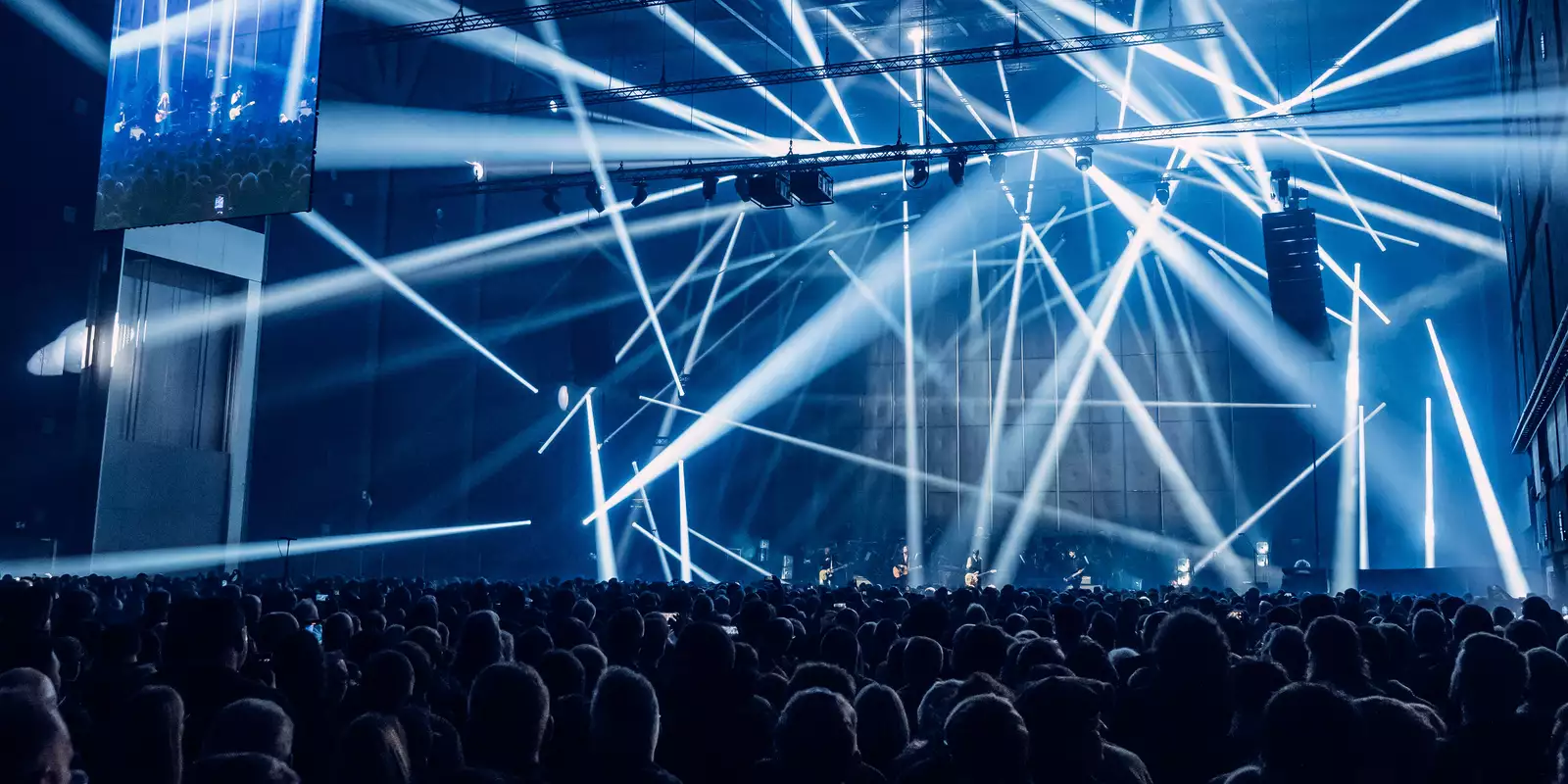 A crowd watching Johnny Marr perform on stage with blue lasers