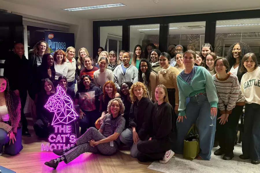 Group photo with a glowing pink sign that reads 'The Cat's Mother'