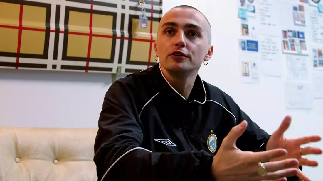 Trackie McLeod talking in his studio with a Burberry patterned artwork behind him