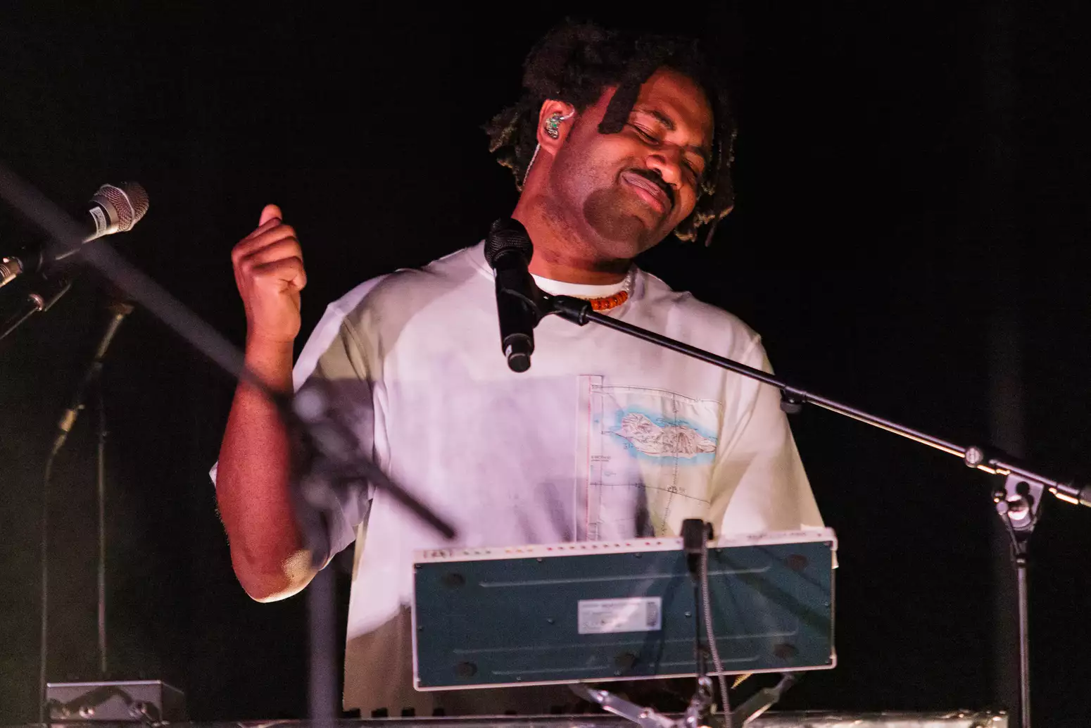 Man performing on stage with 2 microphones, keyboard and synth