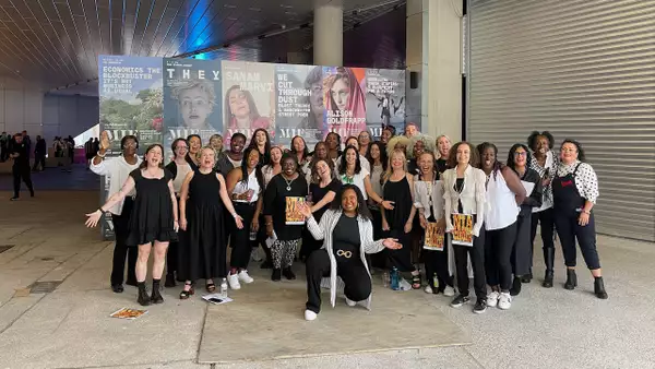 Group photo of NIA Choir, wearing black and white and smiling outside of Aviva Studios