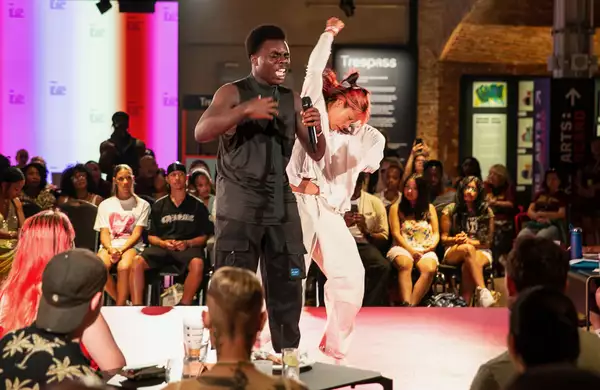 A crowd of people in the Social watching a dancer and poet perform on a stage in the centre