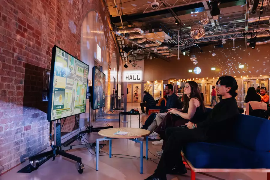 Two people playing on the playstation in the Social. The lighting is dim and disco balls are on display.