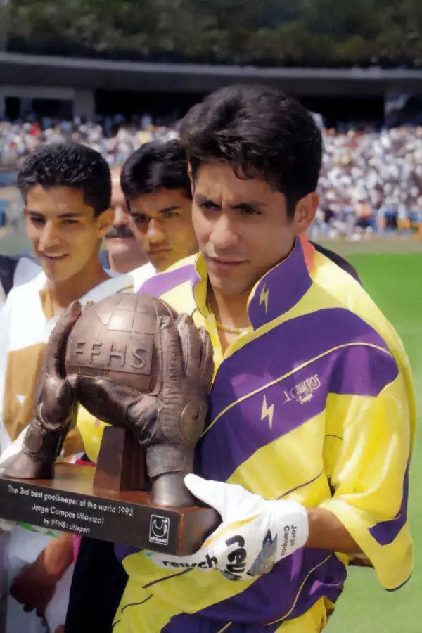 Jorge Campos holding a trophy on a football pitch