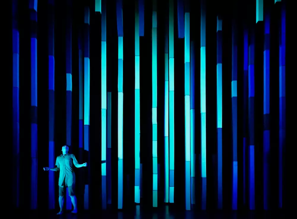 A performer on stage lit with blue beams