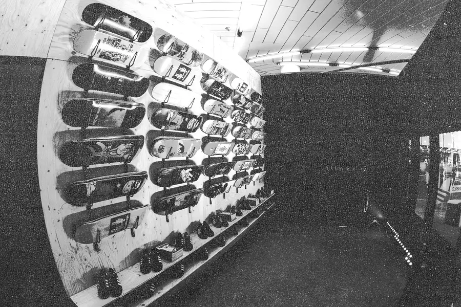 Black and white textured photograph of the Build Manchester pop-up shop in the Undercroft. The shop has shoes and skateboards displayed on the walls.