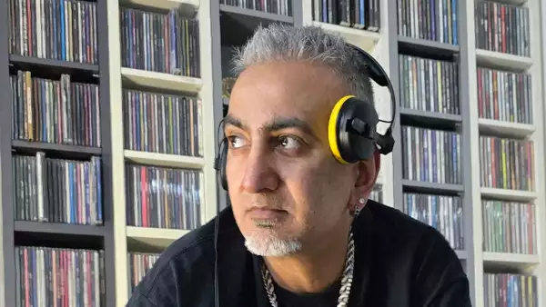 Desi Fusion DJ wearing headphones and stood in front of shelves of records