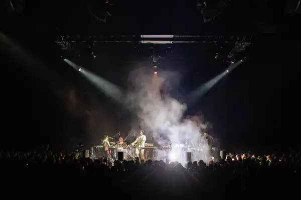 Band on stage with fog and spotlights and silhouettes of crowd