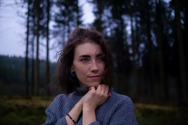 Photo of Caitlin LM wearing a blue jumper in a forest